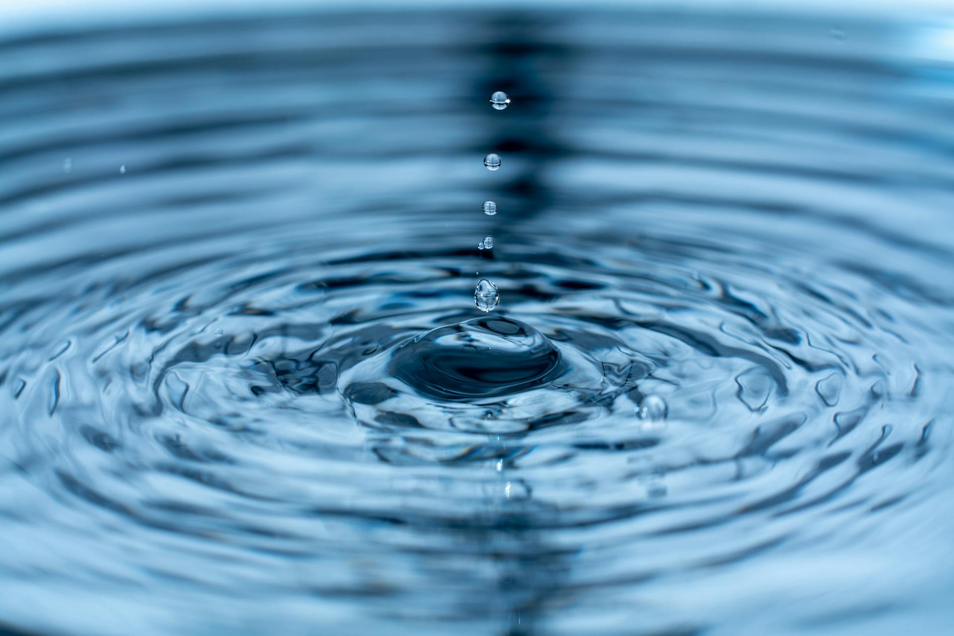 A photograph showing a drop hitting the surface of water and waves spreading out in a circle. This is a symbolic representation of the butterfly effect.
